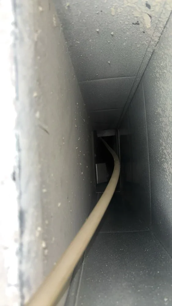 Interior of a metal duct before cleaning with a rod feeding through